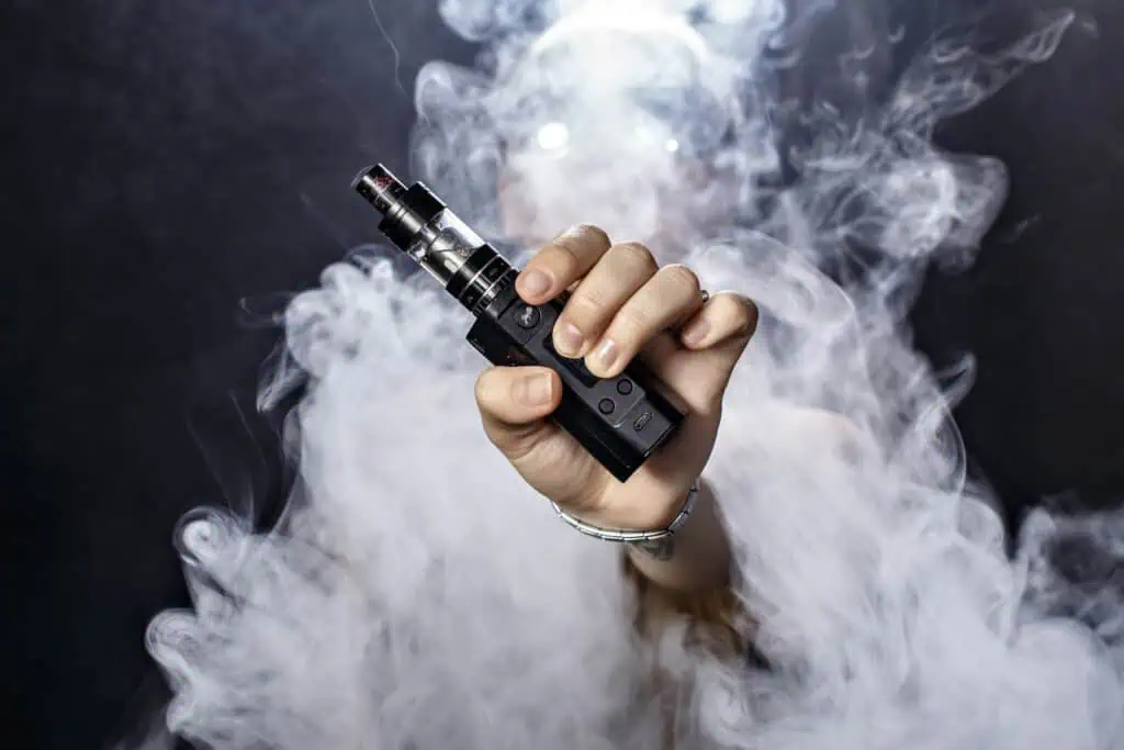 Vape mod y e-líquido con vapor de humo blanco, enfocada en productos para vapear.